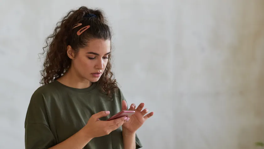 Person standing in front of blank wall while looking at a WhatsApp marketing campaign on phone