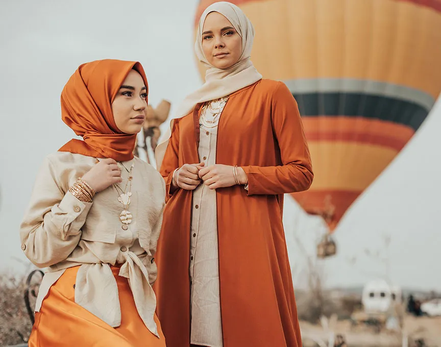 Two stylishly dressed women with a hot air balloon in the background.