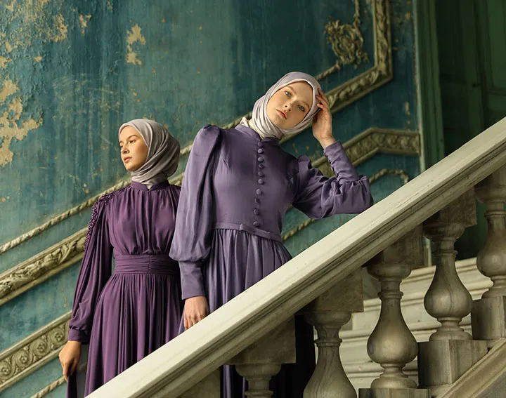 Two elegantly attired women standing on the staircase of an ancient building.