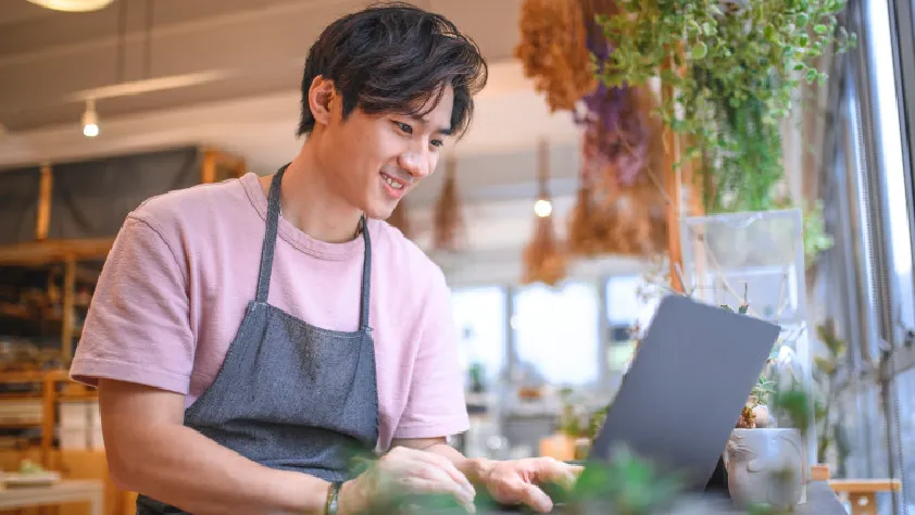 Small business owner working on laptop in their plant shop