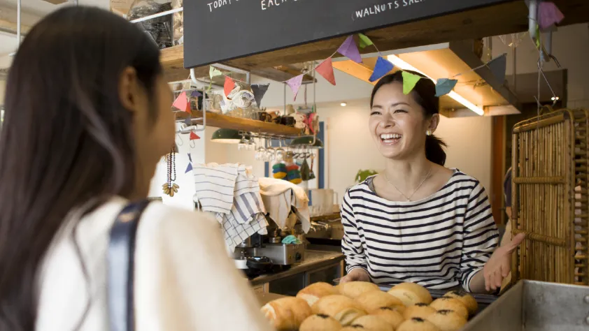 Small business owner selling croissants to a customer in their bakery
