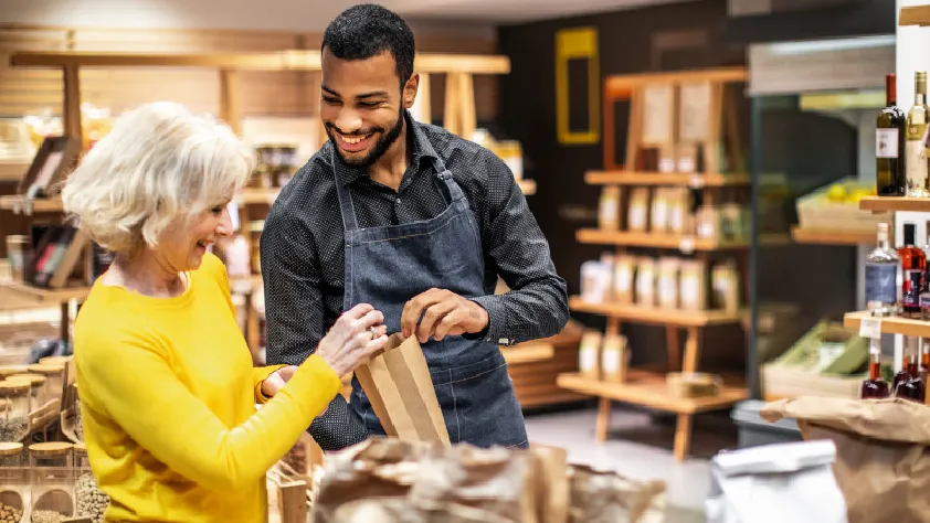 Small business owner selling a bottle of wine to a customer and they are both smiling
