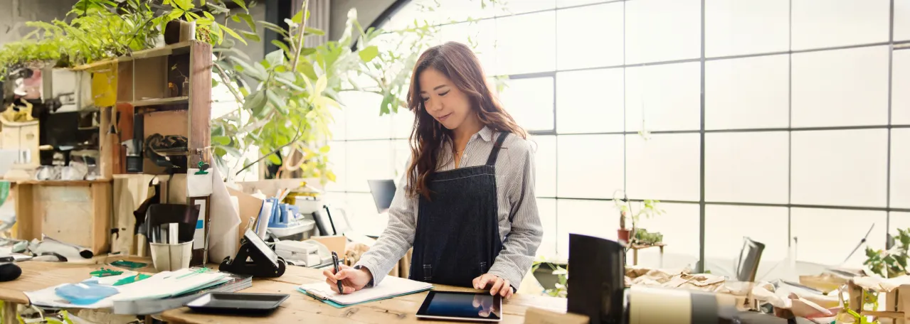 Small business owner writing down orders on a clipboard in plant shop