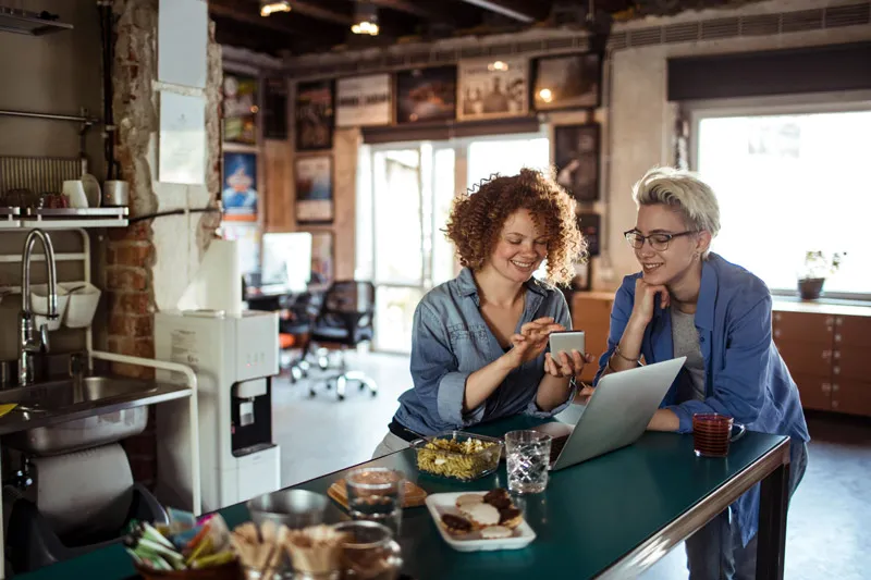 Dos personas en una mesa de cocina de una oficina mirando un teléfono