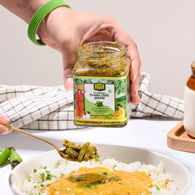 कोई जार से अचार निकालकर चावल की डिश में रख रहा है