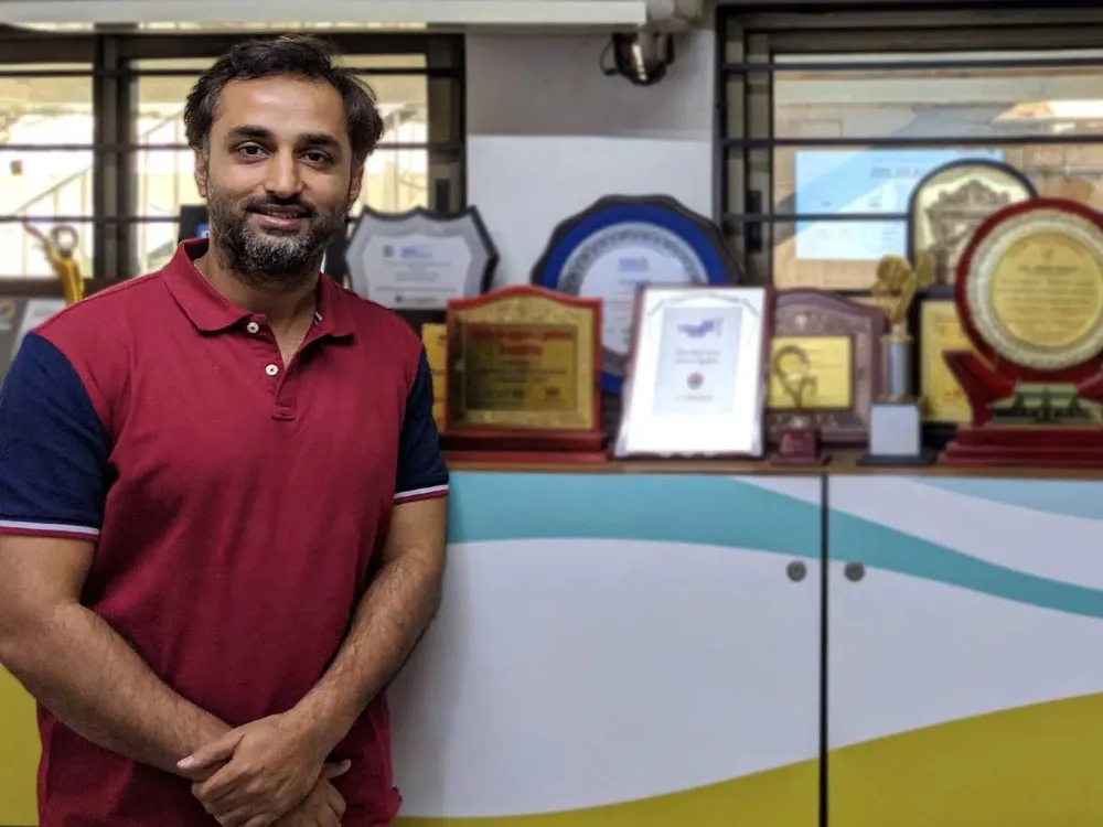 O fundador da CricHeroes em pé ao lado dos troféus