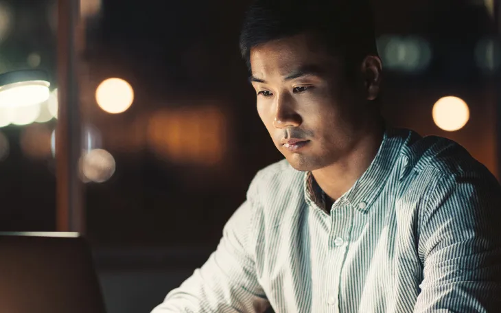 Person sitting at desk working on laptop in the evening