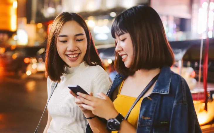 Two women standing on a street, using messaging for support