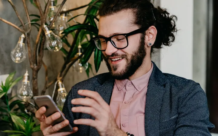 Person smiling at phone while sending a message through WhatsApp