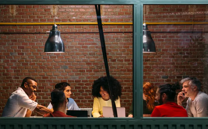 Meeting of seven coworkers occurring in the conference room