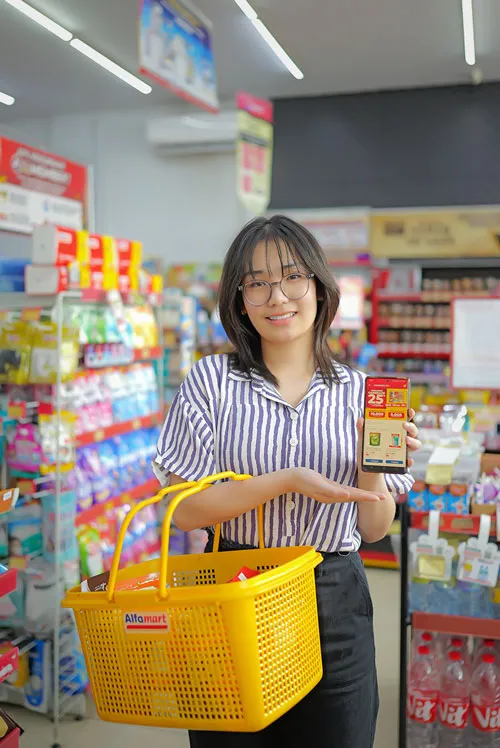 Customer holding a product while standing inside Alfamart store