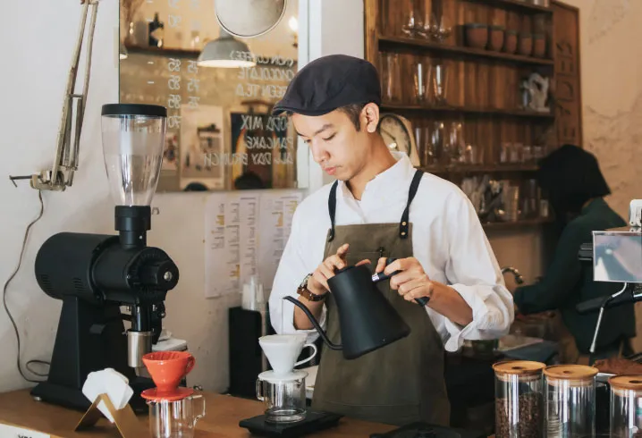 A barista pouring coffee in a café.