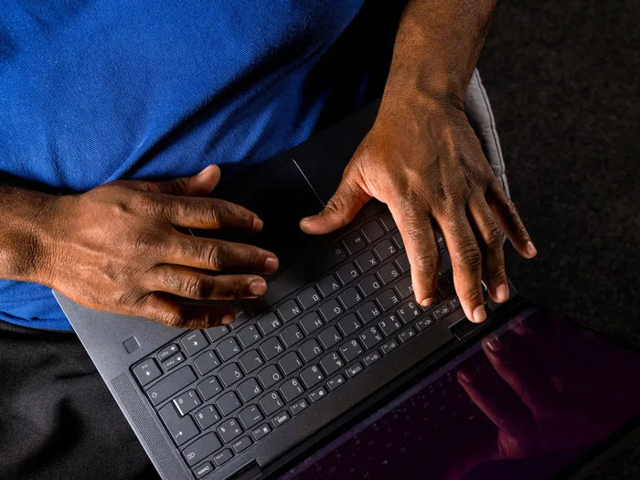 A man's hands resting on his laptop