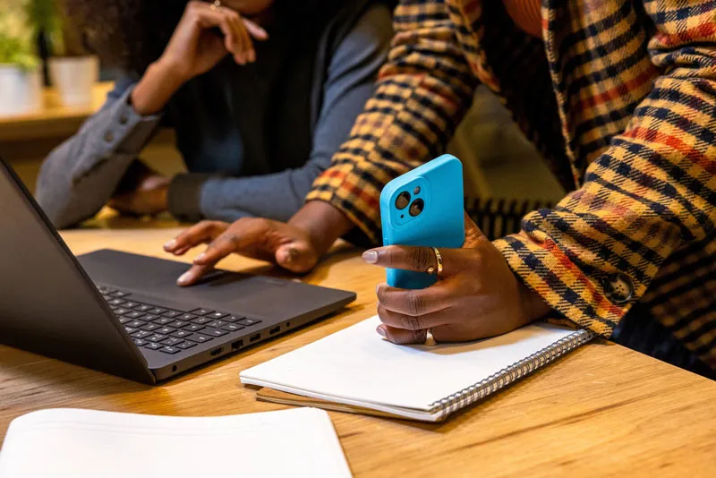 Dua orang sedang fokus di atas meja, keduanya melihat laptop