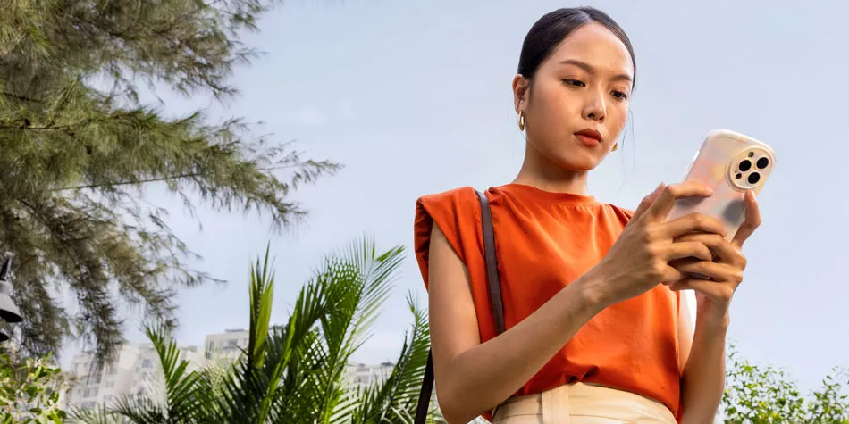 Une femme en extérieur regarde attentivement son téléphone