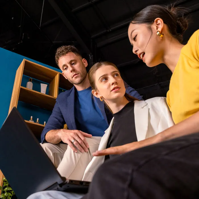 A man and a woman watching a woman share what is on her laptop screen