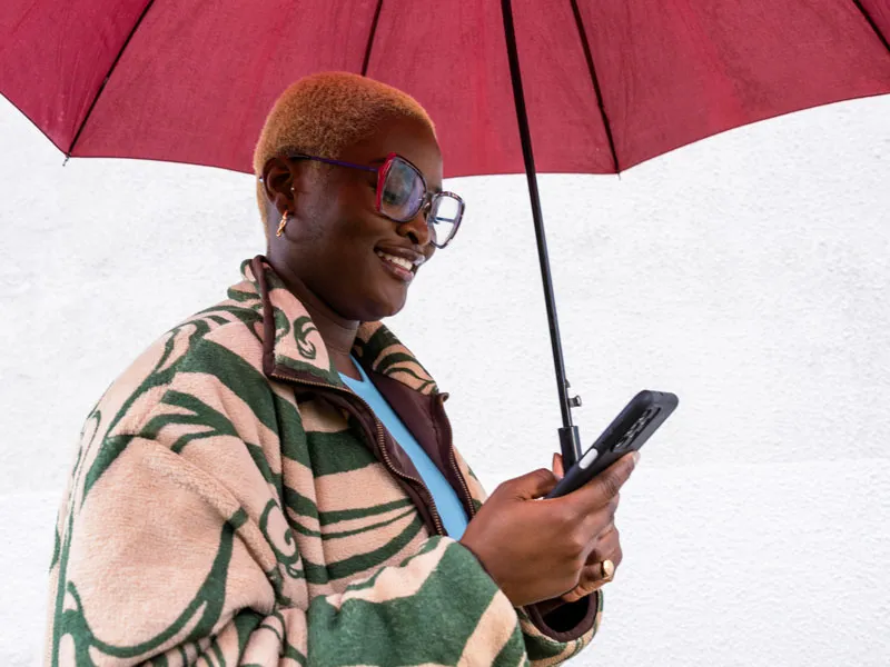 A woman holding an umbrella and looking at her phone