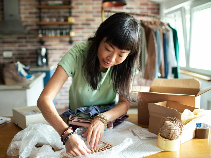 A woman at a tablet adjusting a crafted necklace