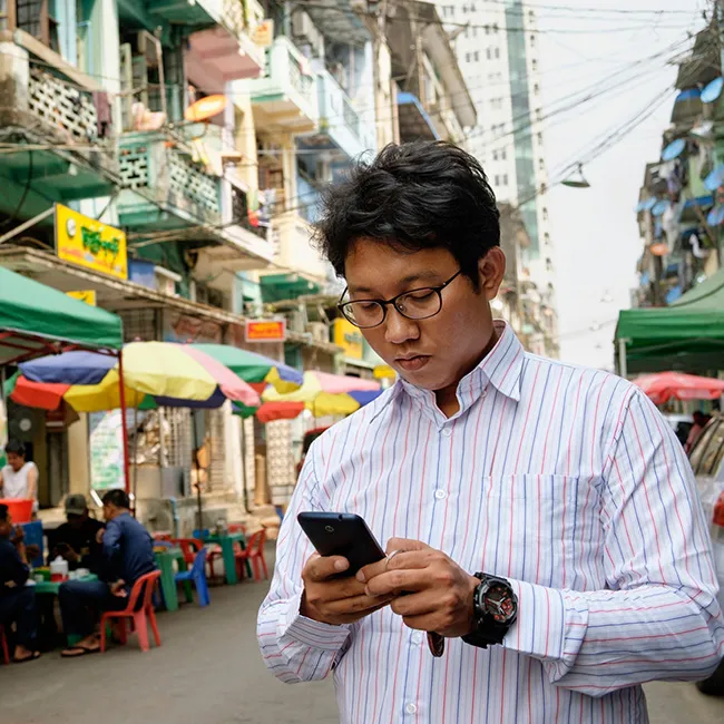 A man looking at this phone while standing in an outdoor commerce area