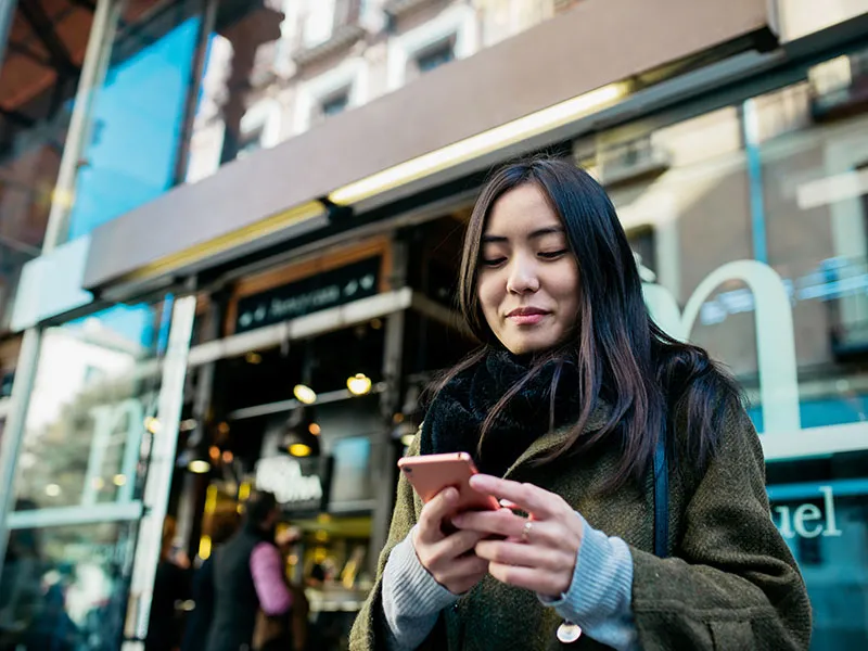 A happy woman using her phone to type a message.