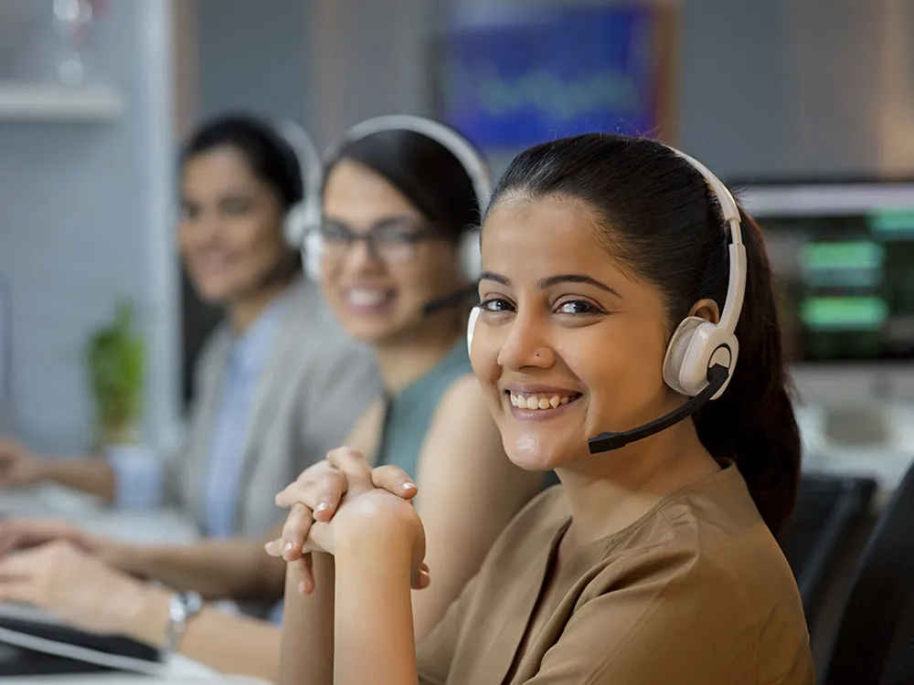 Three call center workers smile while looking at camera
