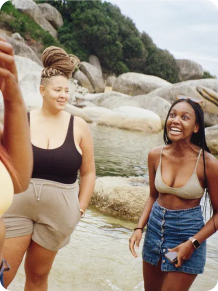 two friends at the beach laughing using whatsapp to connect with friends and family