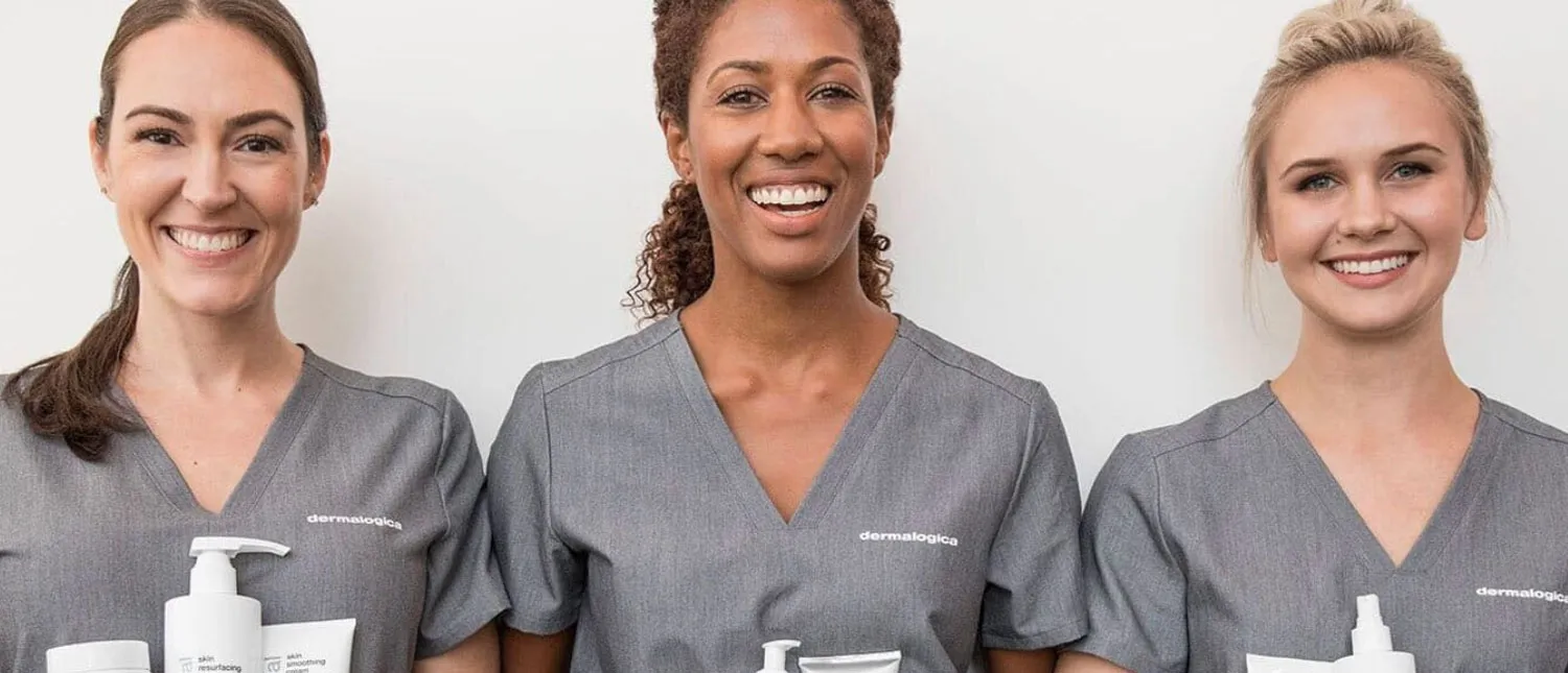 Three dermatologists smiling and holding skincare products