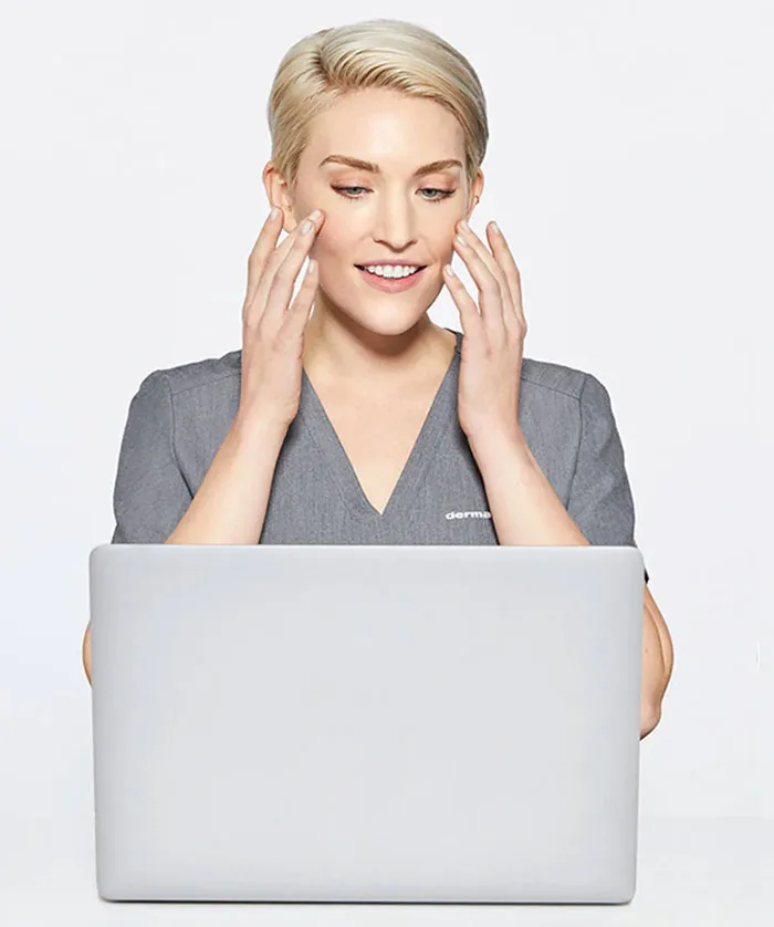 Woman looking at her face using the camera on a laptop computer