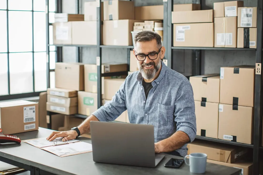 A man in a warehouse working on his laptop