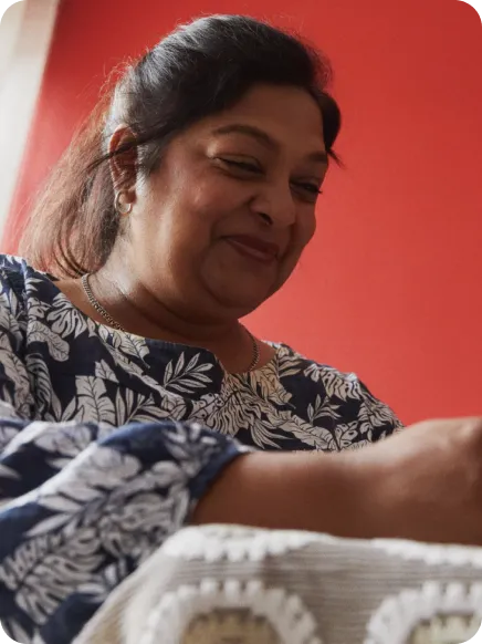 femme qui regarde vers le bas et qui sourit devant son téléphone en utilisant le statut whatsapp