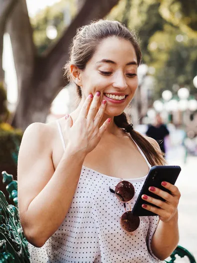Une femme sourit en regardant son téléphone