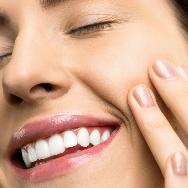 Woman smiling with her eyes closed feeling her face after her skincare routine