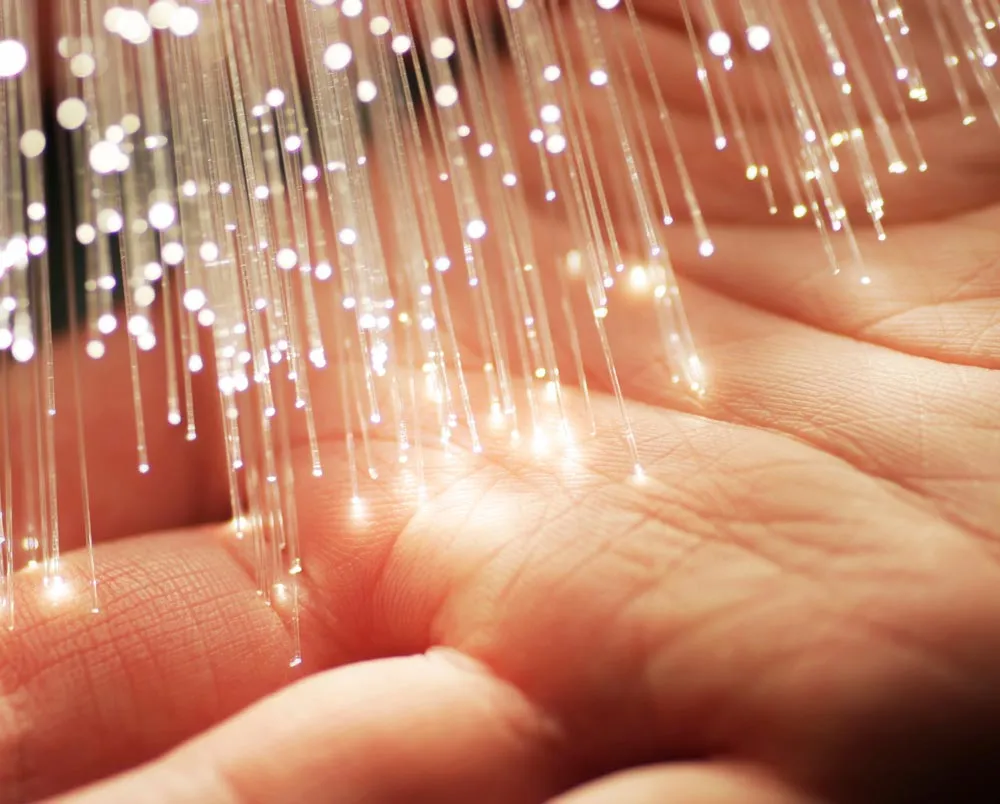 An open palm of a hand under strands of glowing fiber optics