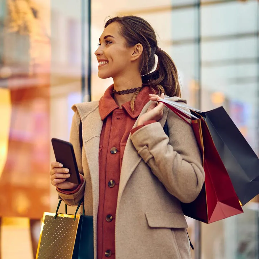 Une femme marche en faisant du shopping et en portant des sacs