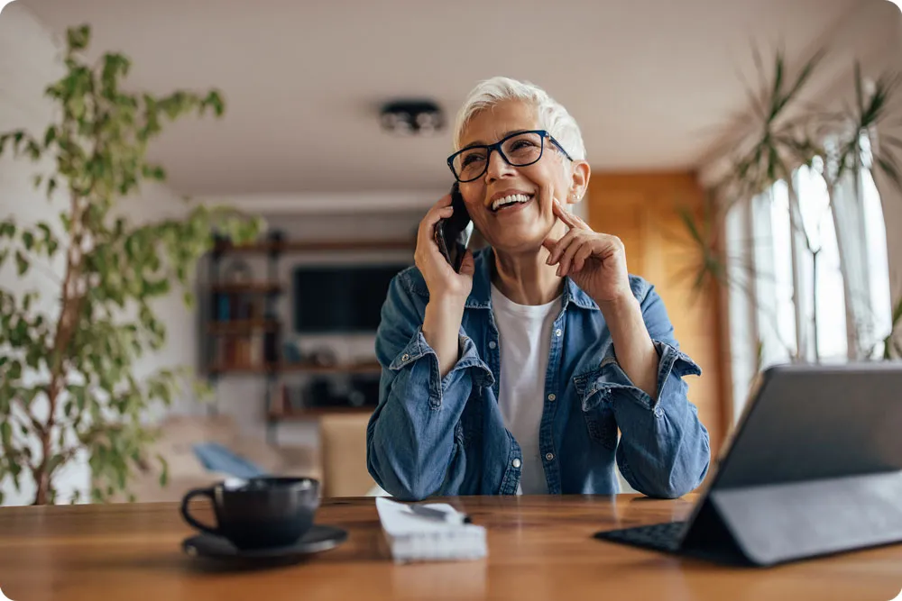 A woman sitting at her table on the phone
