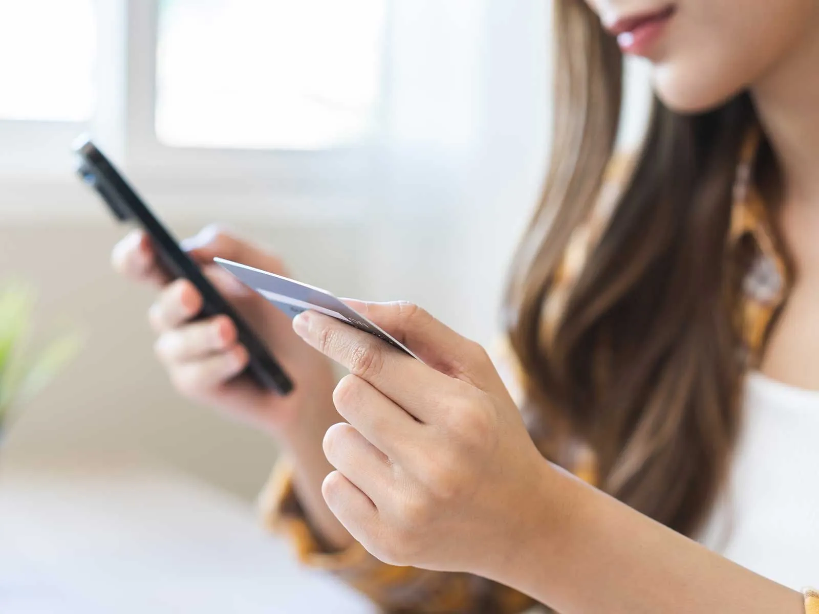 A woman using her mobile phone while entering her credit card information.