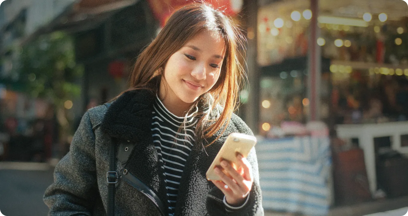 woman in the city stopping to look at the messages on her phone